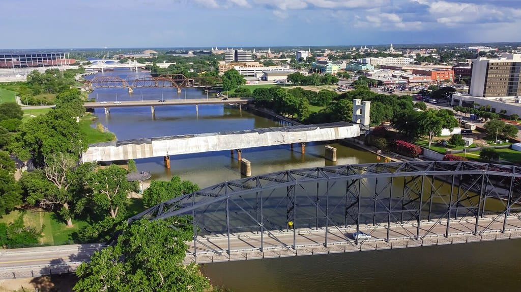 Vista aerea quattro ponti attraversano il fiume Brazos nel centro di Waco, Texas.  Ponti veicolari, ponti ferroviari e ponte sospeso pedonale storico in costruzione con copertura in tela