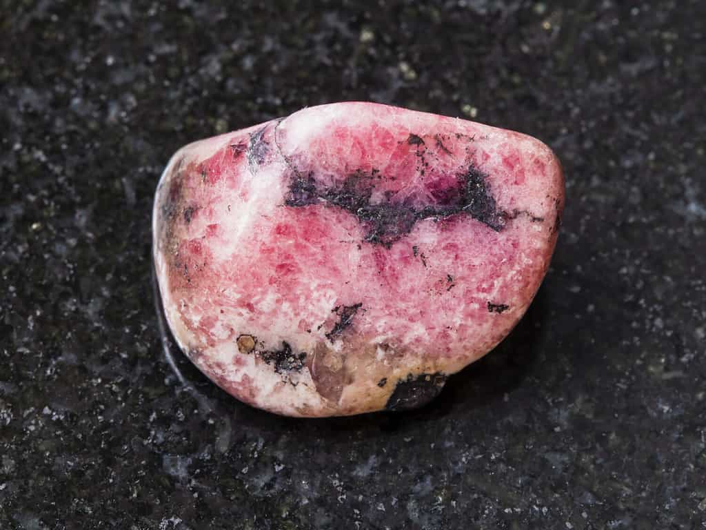riprese macro di esemplari di roccia minerale naturale: pietra preziosa rodonite rosa lucida su sfondo di granito scuro proveniente dai monti Urali in Russia