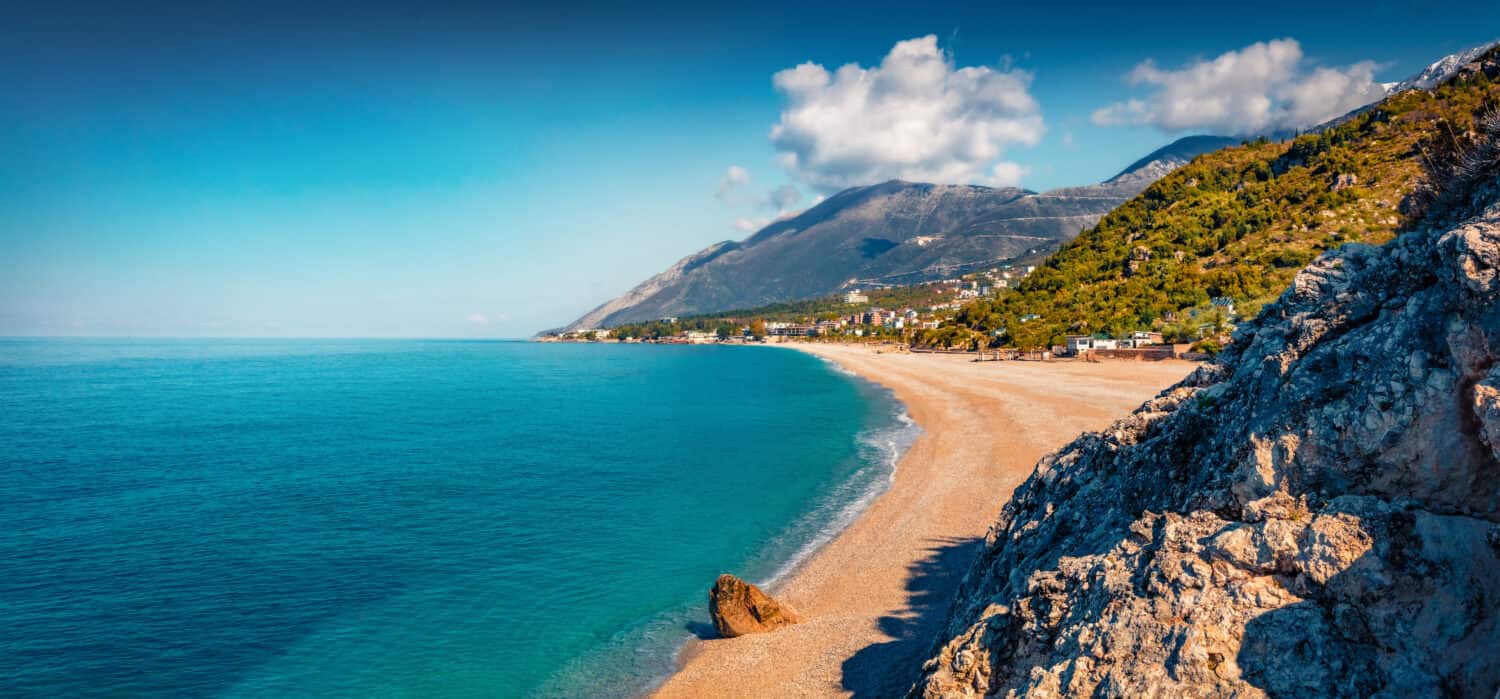 Vista panoramica primaverile della spiaggia pubblica nella città di Dhermi. Vista sul mare variopinta di mattina del mare Adriatico. Attraente scena primaverile dell'Albania, Europa. Sfondo del concetto di viaggio.