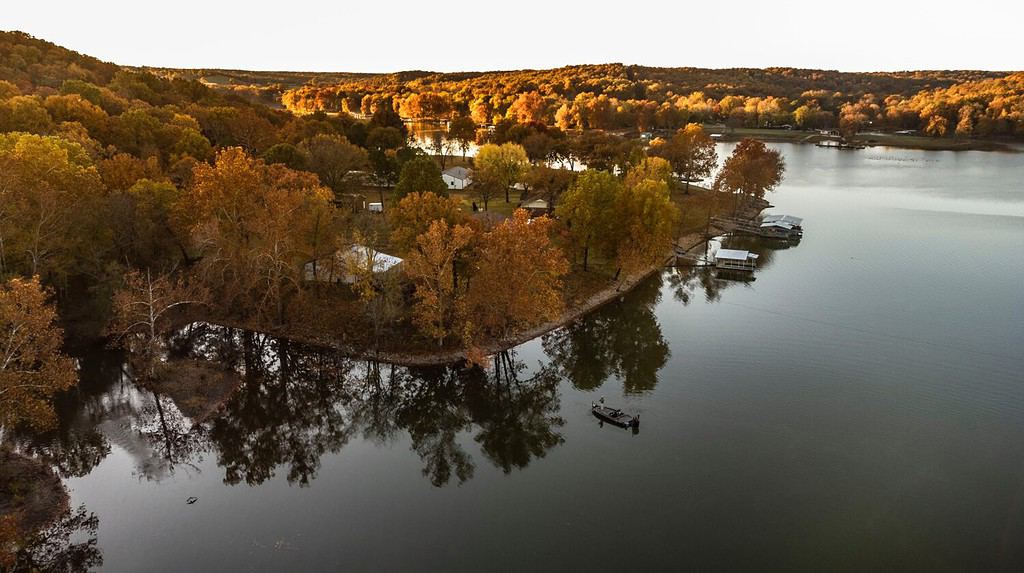 Pescatore che pesca dalla barca durante l'alba autunnale sul Grand Lake in Oklahoma. Foto scattata con drone