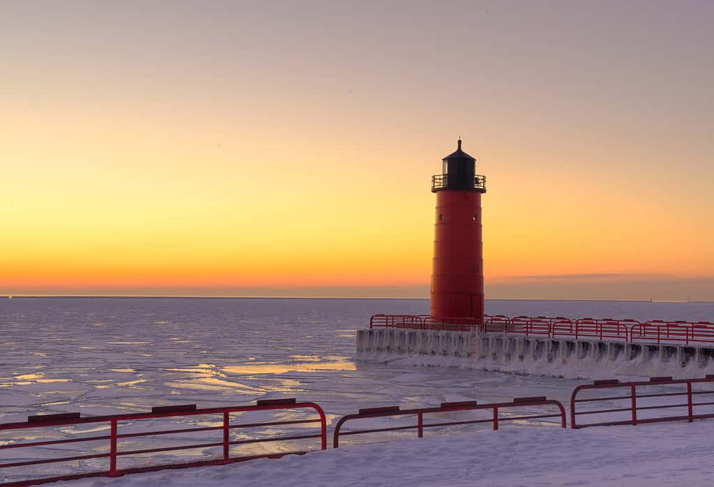 Faro rosso sul lago Michigan in inverno all'alba