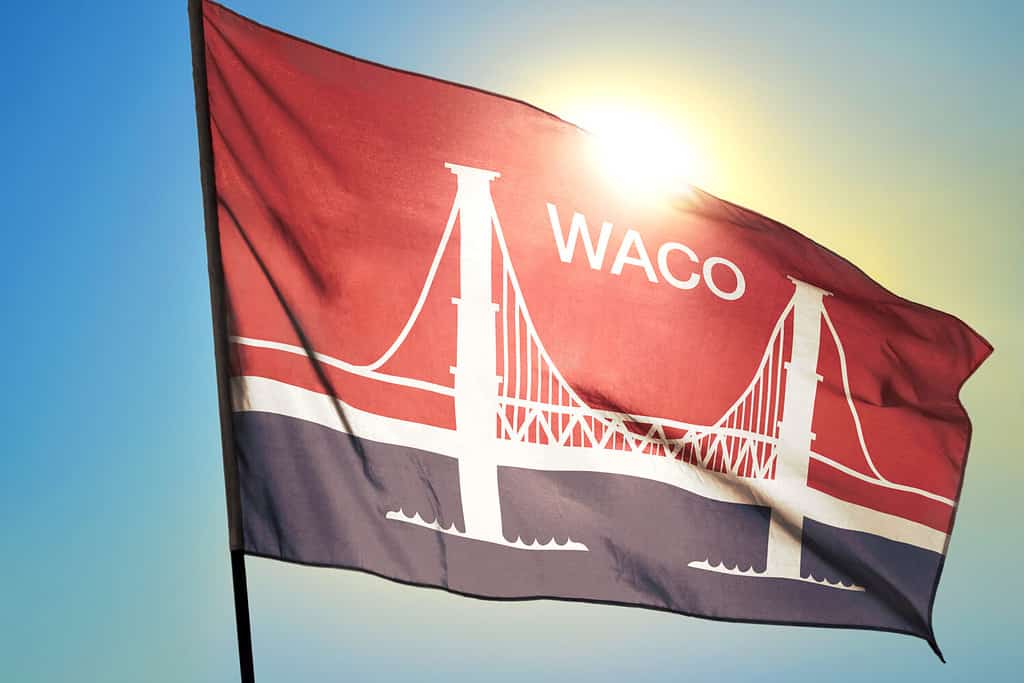 Bandiera di Waco del Texas degli Stati Uniti che sventola nel vento davanti al sole