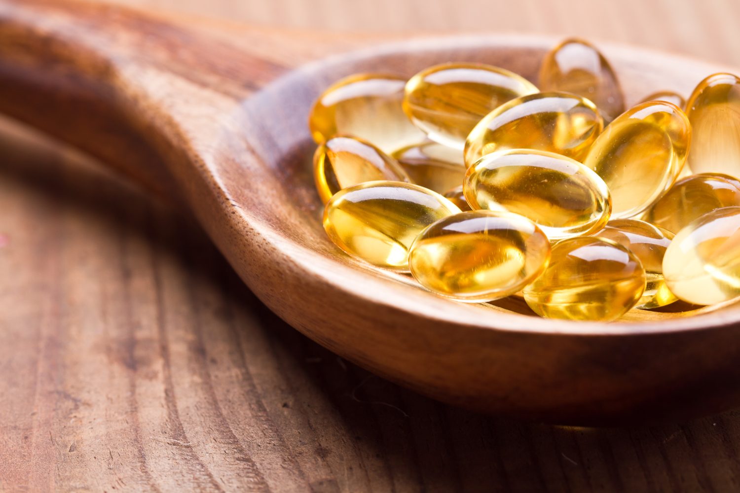 Capsule di gel omega 3 di olio di fegato di merluzzo isolate su sfondo di legno