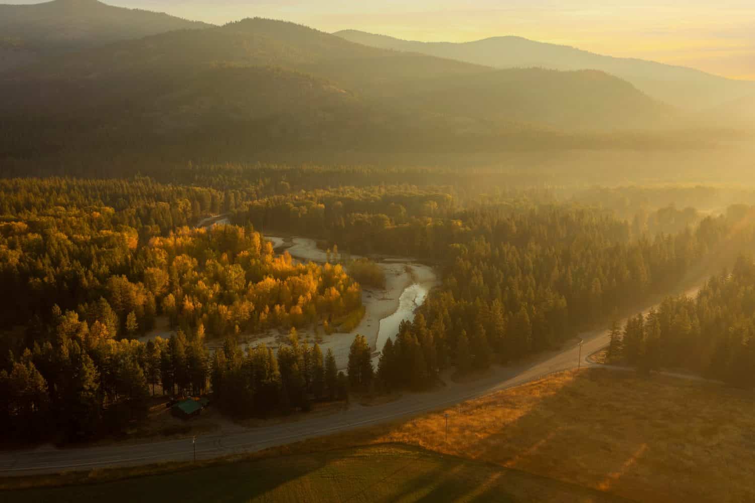 Mattina nebbiosa di caduta sopra il fiume Methow vicino a Mazama, Washington. Vista aerea dei droni all'alba della storica Methow Valley con viste colorate degli alberi di pioppo tremulo che cambiano nei loro colori autunnali.