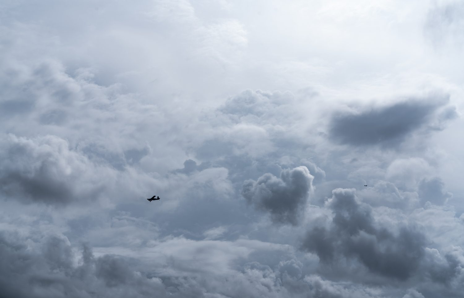 Piccolo aereo nel cielo nuvoloso per la produzione di pioggia. Nuvole bianche e soffici con piccoli aerei per produrre piogge artificiali. Due aerei che volano sul cielo nuvoloso. Aereo agricolo per precipitazioni artificiali.
