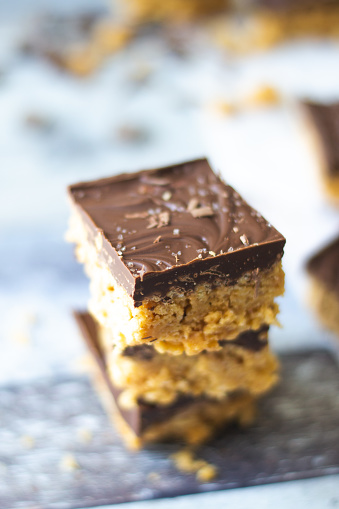 Angolo laterale dello Scotcheroo al burro di arachidi impilato e impilato su uno sfondo di legno invecchiato grigio blu.