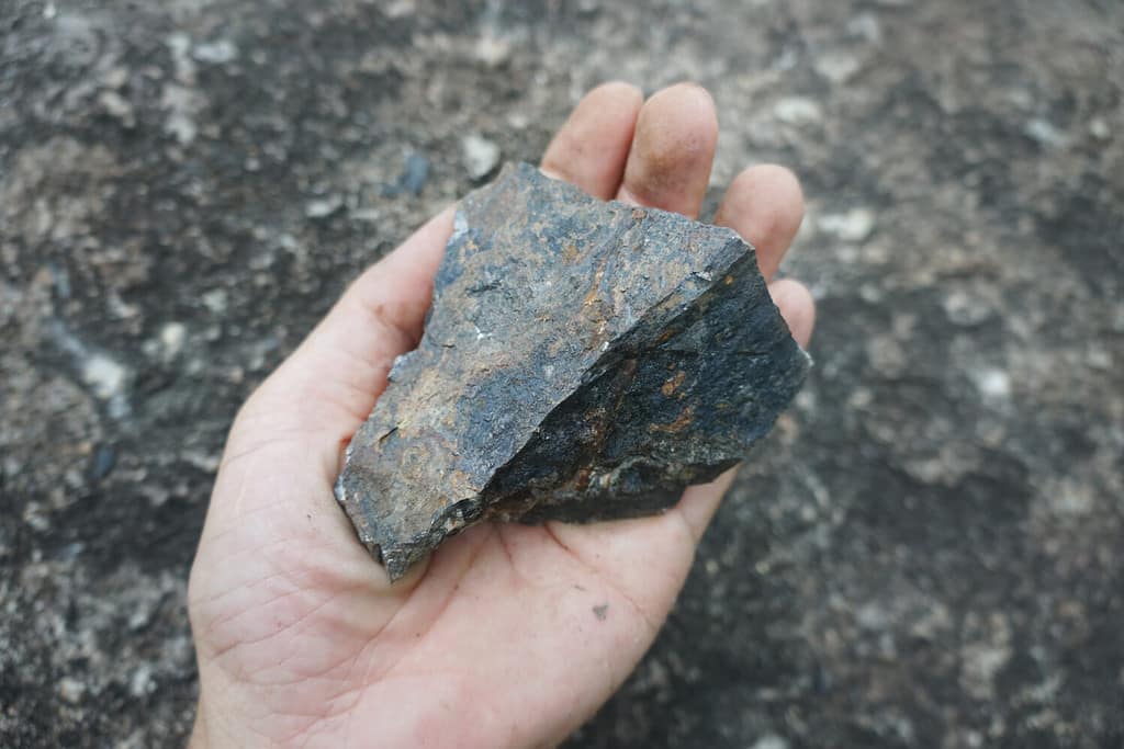 Una mano che tiene la pietra di ematite. pietra di ferro.