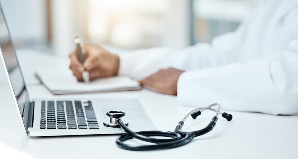 Laptop, stetoscopio e medico scrivono su un taccuino per la pianificazione della ricerca o l'innovazione della tecnologia medica nell'ufficio ospedaliero. Operatore medico sanitario, appunti sul libro della strategia di ricerca e comunicazione online