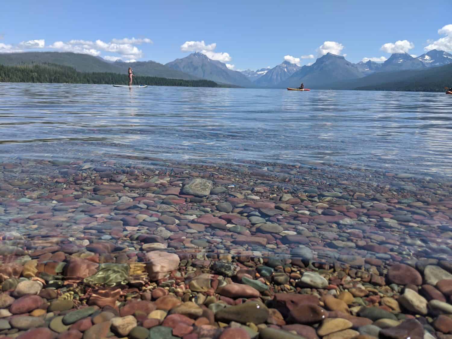 La colorata riva rocciosa del lago McDonald nel Glacier National Park guardando le montagne.