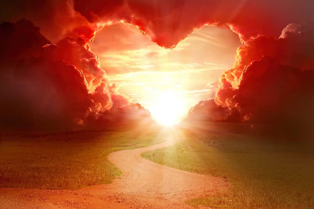 Cielo a forma di cuore rosso al tramonto. Bellissimo paesaggio con strada e nuvole. Sfondo amore con spazio per la copia. Strada per amare