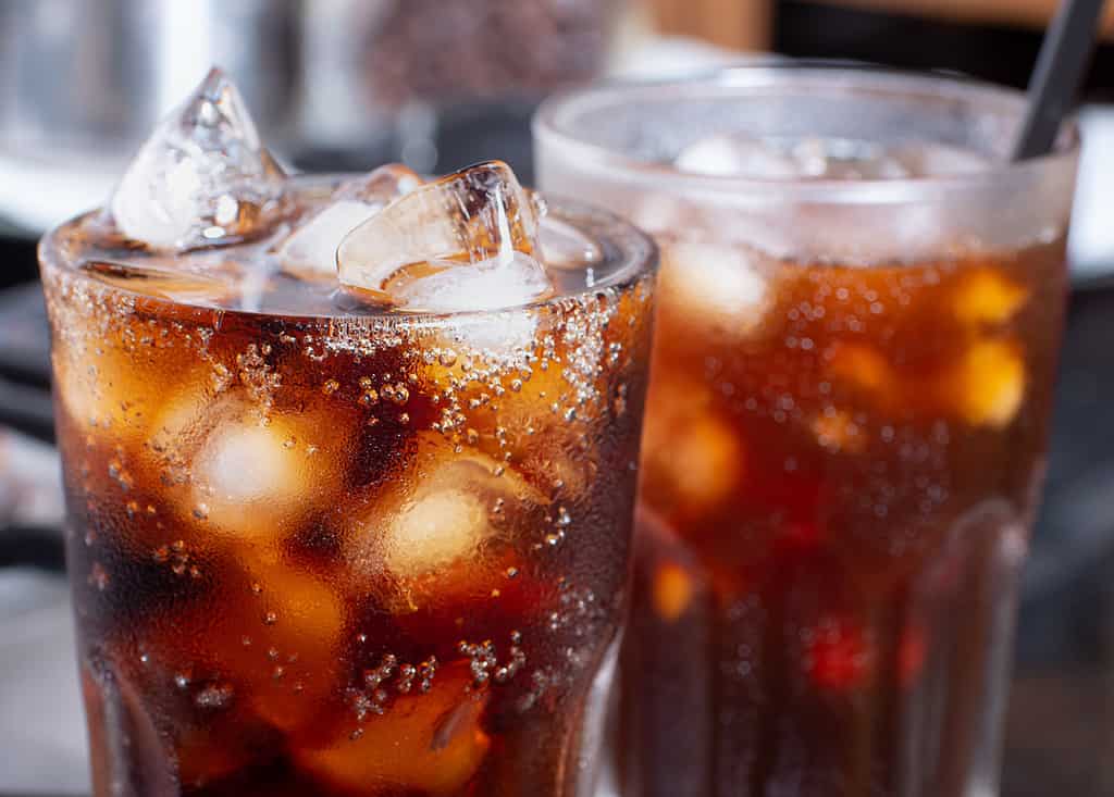 Cola con ghiaccio tritato nel bicchiere e ci sono gocce d'acqua intorno. bevanda fresca nera fresca.