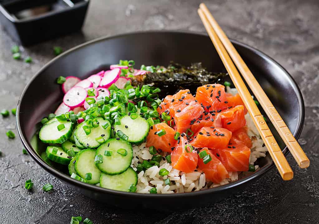 Poke Bowl di pesce salmone hawaiano con riso, ravanello, cetriolo, pomodoro, semi di sesamo e alghe. Ciotola del Budda. Cibo dietetico