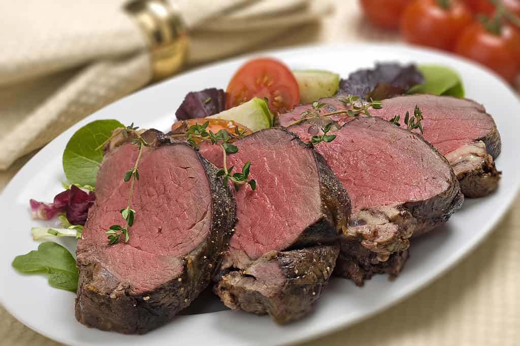 Filetto di bisonte su piatto bianco con contorni di insalata