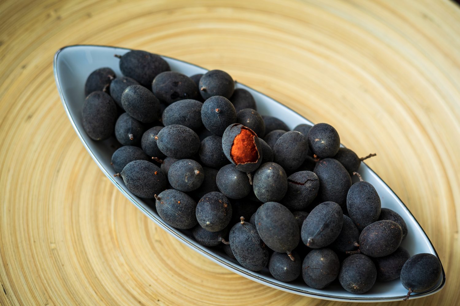 Frutto di tamarindo vellutato (Dialium cochinchinense) o buah keranji su uno sfondo di piatto di bambù di legno.