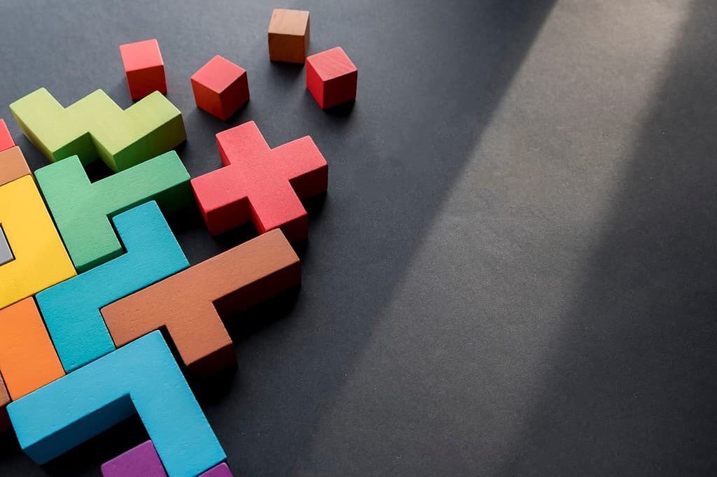 Blocchi di legno di diverse forme colorate su sfondo nero, disposizione piatta. Forme geometriche in diversi colori, vista dall'alto. Concetto di pensiero creativo, logico o risoluzione dei problemi. Copia spazio.