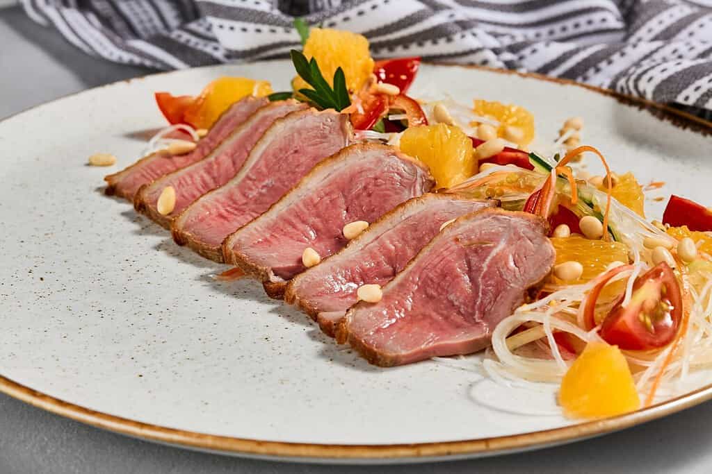 Insalata sana con carne di anatra, arancia e verdure. Cibo cinese: insalata di anatra con agrumi e condimento fresco. Tagliata di carne d'anatra con verdure croccanti e pinoli