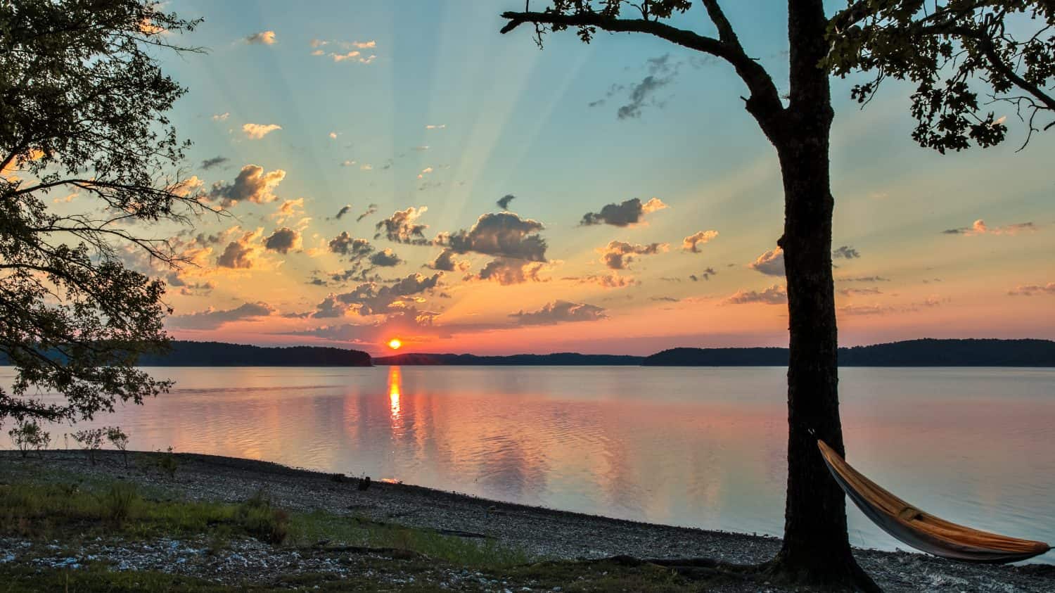 Amaca sulla spiaggia rocciosa guardando una bellissima alba sul lago Ouachita