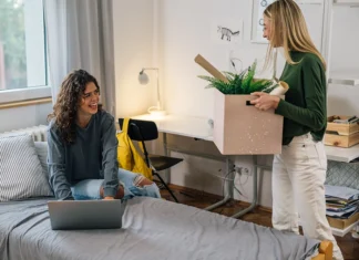 Two female college students smile as they move into their new dorm.